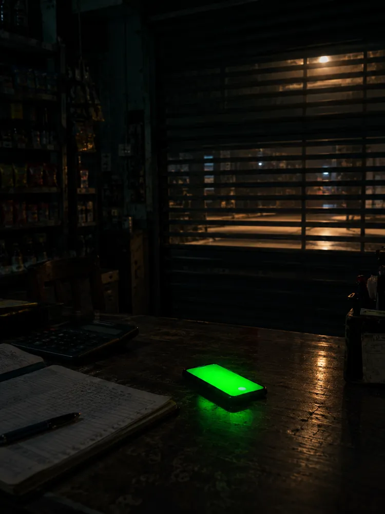 Phone lighting up on a shop counter at 2 am, shop shutter closed
